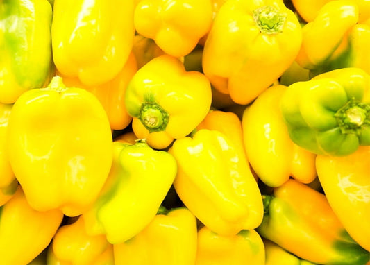 Nahaufnahme eines Haufens glänzender frischer gelber Paprika