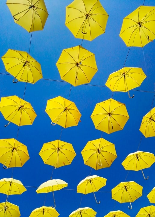 Reihen offener gelber Regenschirme vor strahlend blauem Himmel