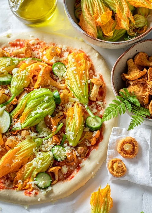 Pizza mit Zucchiniblüten, Pfifferlingen und geriebenem Käse