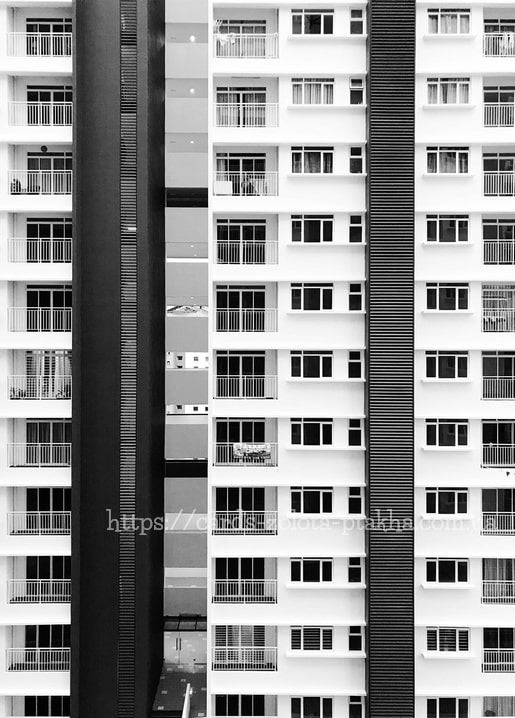 High-rise facade with rows of balconies, split by dark vertical bands