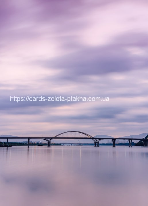 Bogenbrücke über stillem Wasser bei pastellrosa Dämmerung