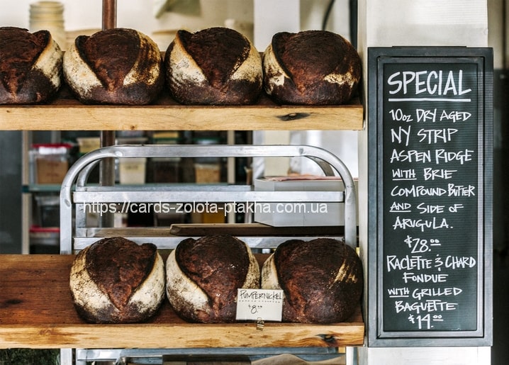 Dunkle Sauerteigbrote im Bäckereiregal vor einer Tafel mit Tagesangeboten