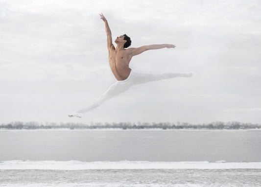 Balletttänzer springt im Grand Jeté über einen zugefrorenen Wintersee