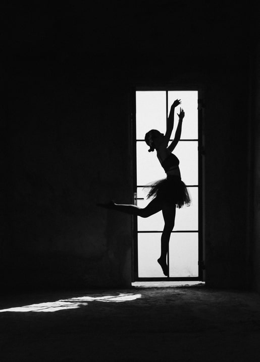 Silhouette einer springenden Ballerina in einem hohen Sprossenfenster, Schwarzweißfoto