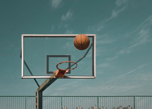 Basketball fliegt über ein Glasbrett vor türkisfarbenem Himmel