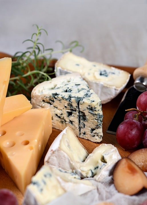 Nahaufnahme von Blauschimmelkäse und Camembert mit Rosmarin, Trauben und Pflaume