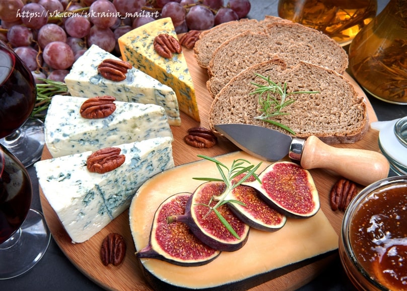 Blue cheese wedges with pecans, rye bread, figs, and red wine on a wooden board