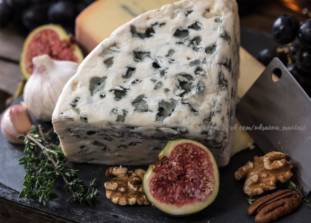 Stück Blauschimmelkäse mit Feigen, Walnüssen und Knoblauch auf Schiefer