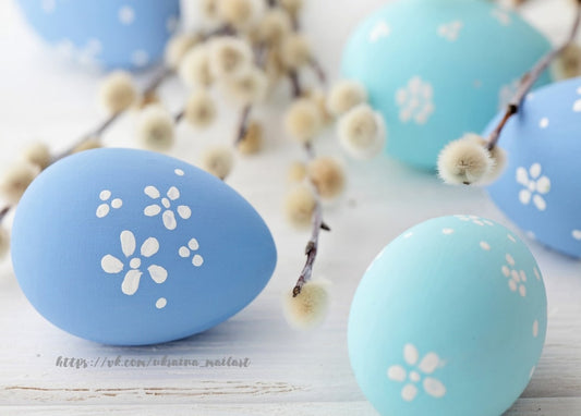 Pale blue eggs with white flower designs beside fluffy pussy willow branches