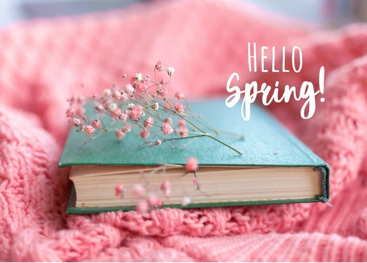 Grünes Buch mit rosa Schleierkraut-Zweigen auf einer Strickdecke