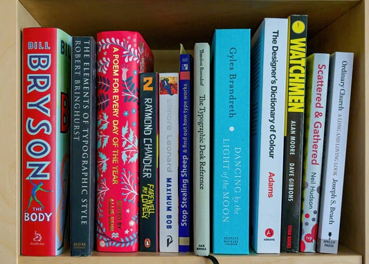 Полиця зі світлого дерева з книгами з дизайну та яскравою графічною новелою