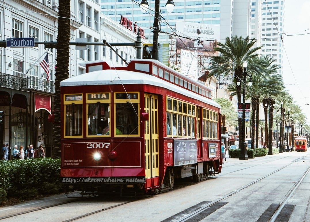 Rote RTA-Straßenbahn Nummer 2007 auf der Bourbon Street in New Orleans mit Palmen im Hintergrund