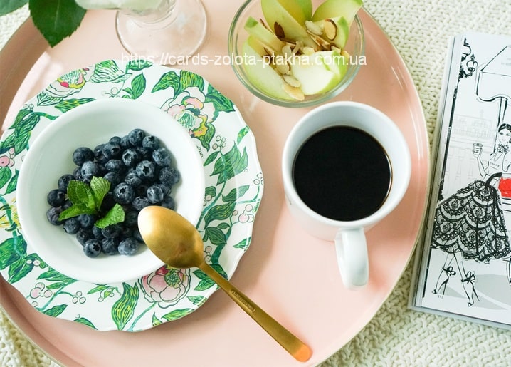 Frühstückstablett mit Blaubeeren, schwarzem Kaffee, Apfelspalten und Mode-Skizzenbuch