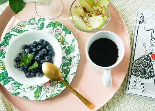 Frühstückstablett mit Blaubeeren, schwarzem Kaffee, Apfelspalten und Mode-Skizzenbuch