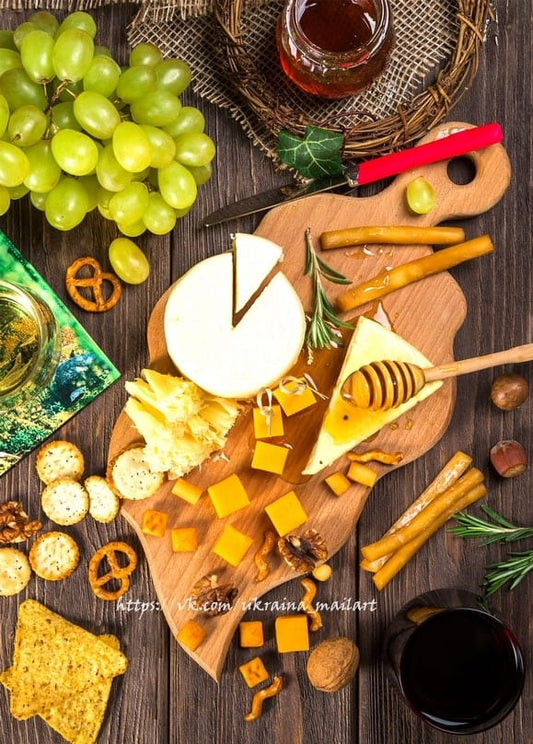 Angeschnittener Brie, grüne Trauben, Honigglas, Haselnüsse und Brezeln auf Holzbrett