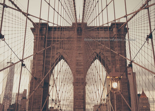 Steinturm und Kabel der Brooklyn Bridge vor der Skyline Manhattans in der Dämmerung