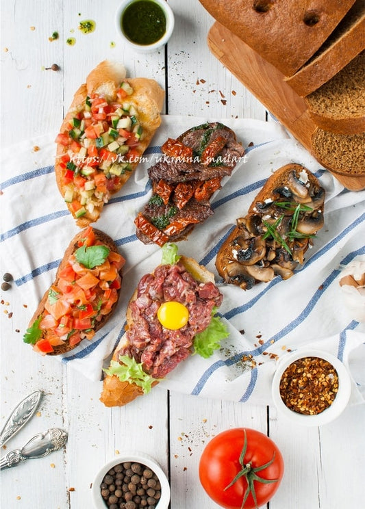 Bruschetta-Auswahl mit Tomate, Pilzen und Rindertatar mit Eigelb auf einem Brotbrett