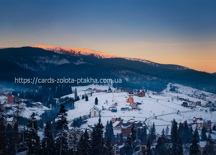 Bukovel ski village at dusk with alpenglow on the mountain peak and a chairlift in the valley