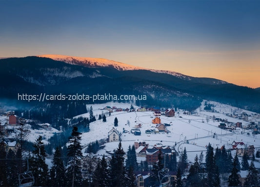 Bukovel ski village at dusk with alpenglow on the mountain peak and a chairlift in the valley