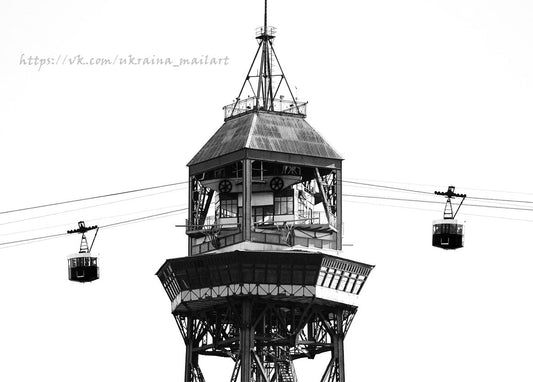 Black-and-white photo of a cable-car station tower with two gondolas passing on cables