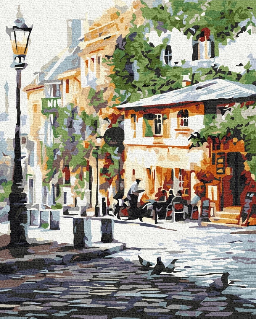 Illustrated street corner with a lamppost, café terrace under trees, and pigeons on cobblestones