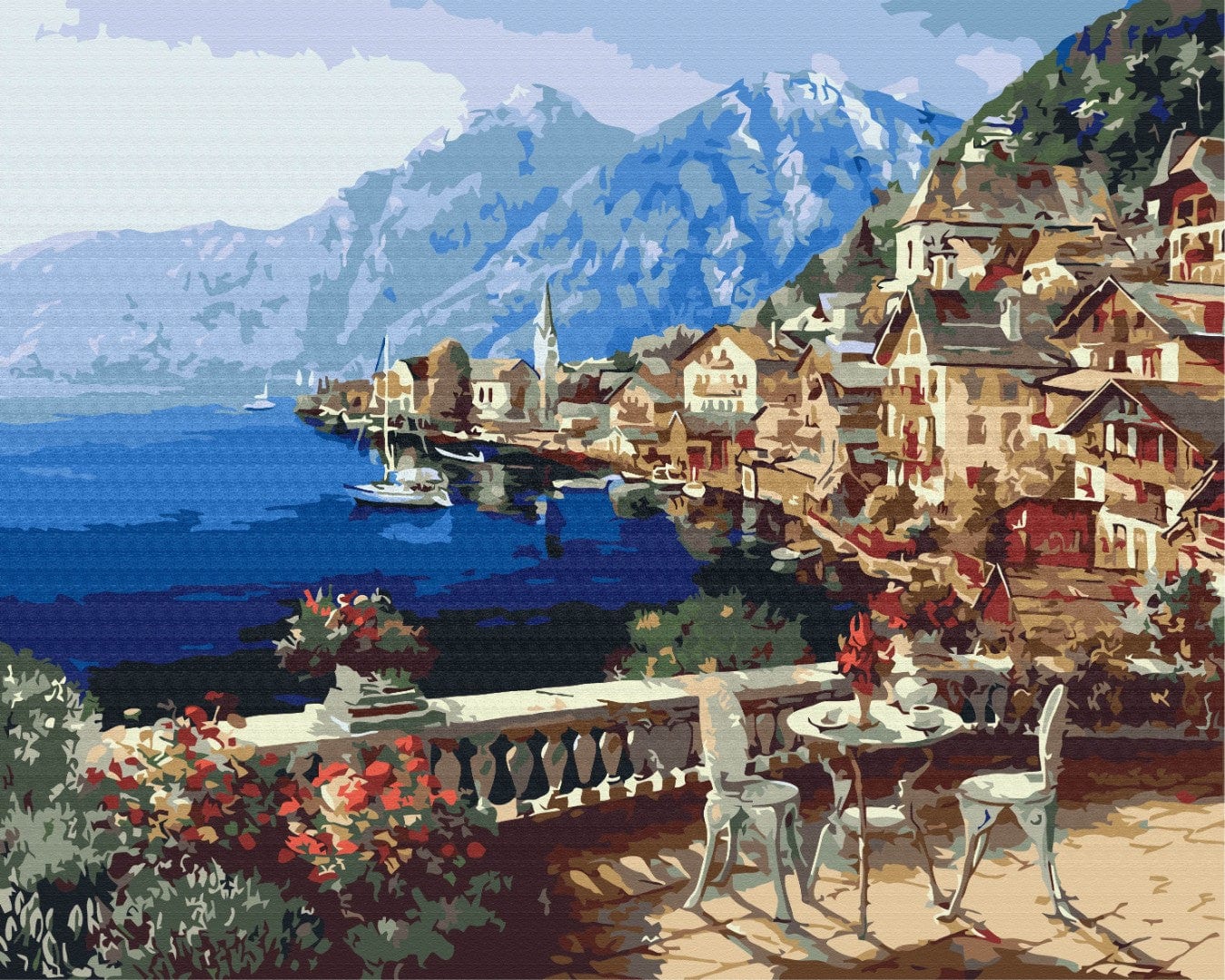 Café terrace with red geraniums overlooking an Alpine lakeside town and mountains