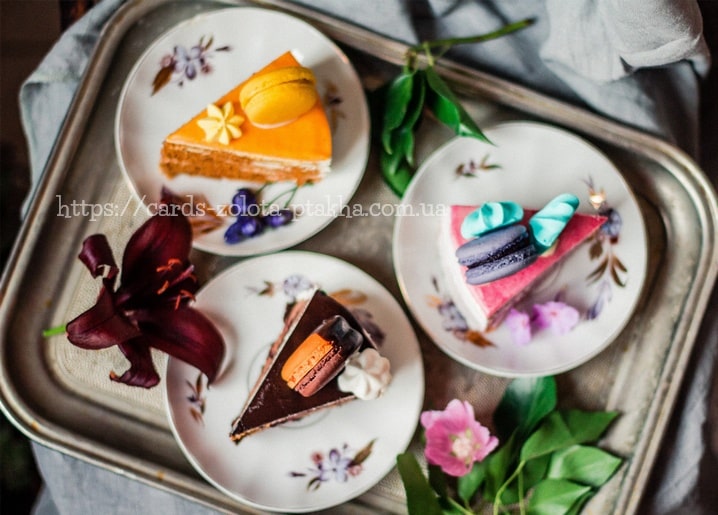 Drei Kuchenstücke mit Macarons auf floralen Vintage-Tellern mit einer Lilie