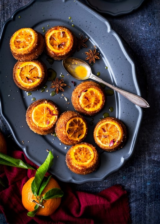 Candied orange cakes with star anise and syrup on a dark plate
