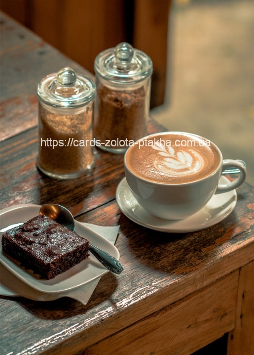 Cappuccino mit Latte-Art, Schokoladen-Brownie und Zuckerdosen auf einem rustikalen Holztisch