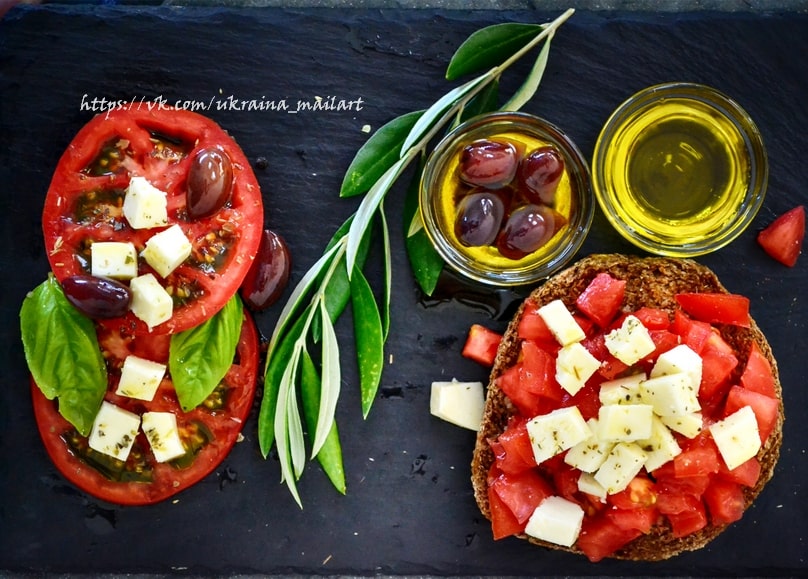 Caprese salad with tomato and mozzarella beside olive bruschetta and a bowl of olive oil