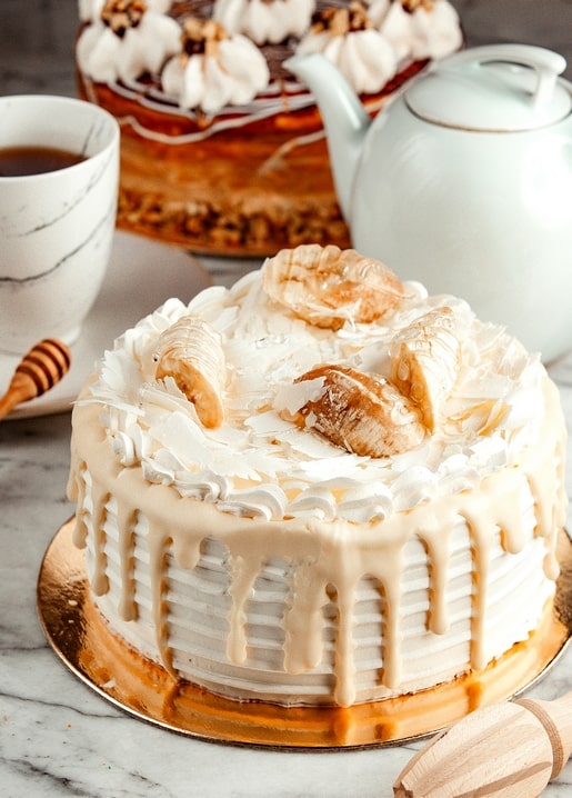 Caramel banana cake beside a tea cup, honey dipper, and white teapot