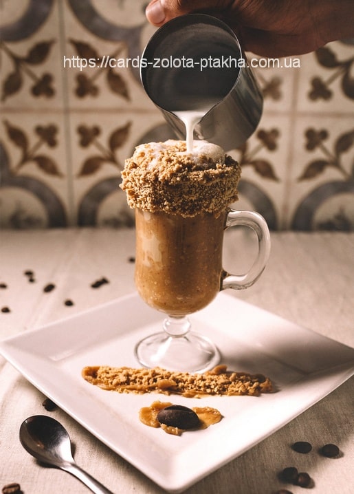 Hand pouring cream over a caramel coffee dessert in a glass mug