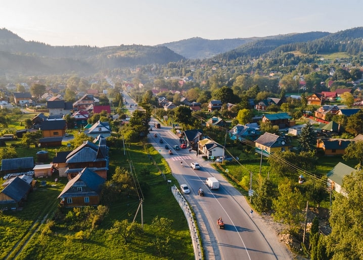 Вигляд з висоти на карпатське село зі звивистою дорогою серед зелених пагорбів