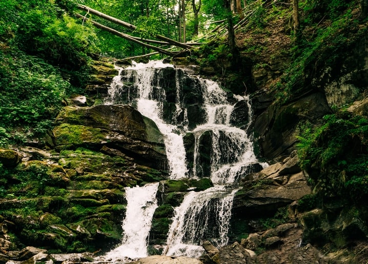 Багатоярусний водоспад серед замшілого каміння в Карпатах