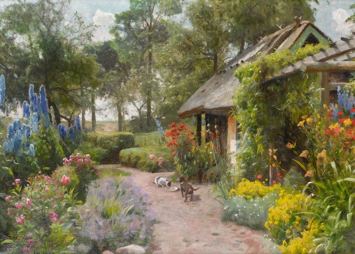 Zwei Katzen auf einem Gartenweg vor blauem Rittersporn und Cottage