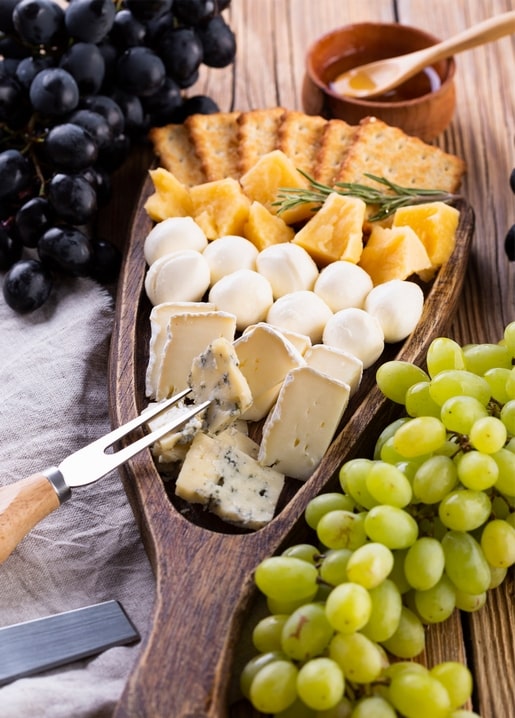 Käseplatte mit Cracker, Mozzarella, Brie und schwarzen sowie grünen Trauben