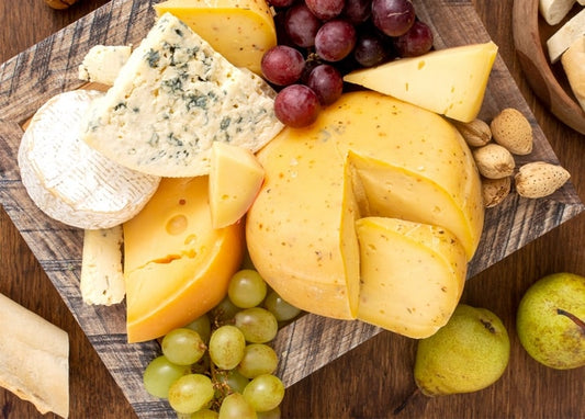 Käseplatte von oben mit Camembert, Blauschimmelkäse, Trauben, Birnen und Mandeln
