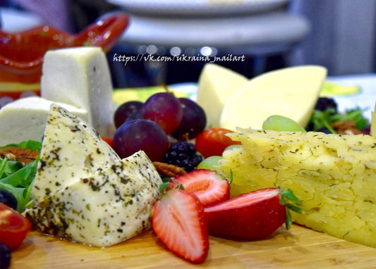 Herbed cheese wedges with red and black grapes, strawberries, and blackberries on a wooden board