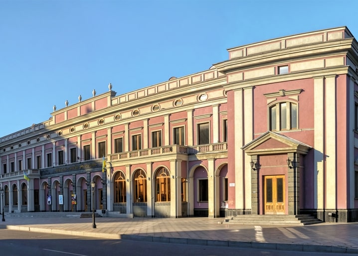 Pink neoclassical building with columns in Cherkasy at golden hour