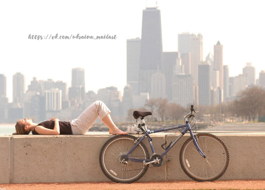Frau ruht an einer Mauer am See neben ihrem Rad vor der Skyline Chicagos