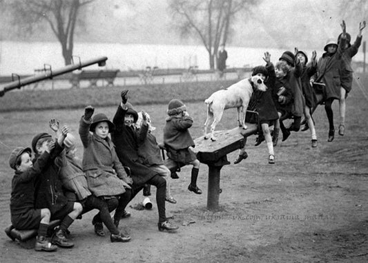 Vintages Foto: Kinder auf einer Parkbank heben die Hände, ein Hund steht mitten unter ihnen, im Hintergrund ein nebliger See