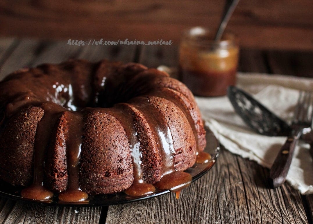 Schokoladen-Gugelhupf mit Karamellsauce neben einem Glas Karamell