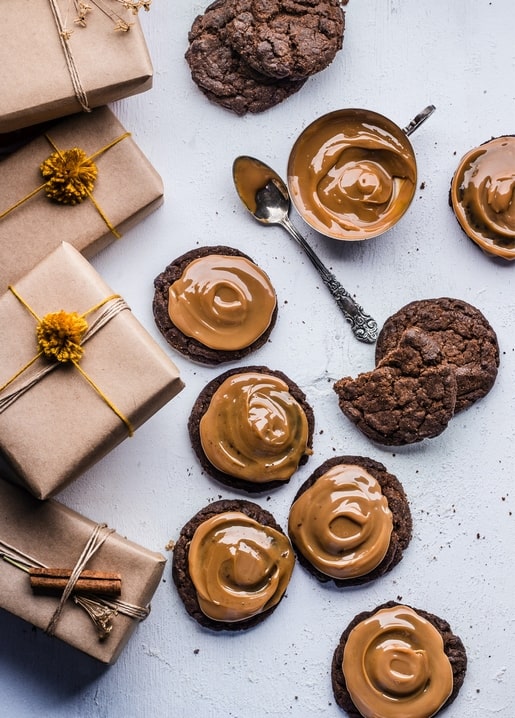 Schokoladenkekse mit Karamell neben Geschenkboxen aus Kraftpapier und Zimtstange