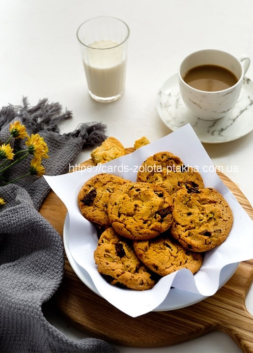 Teller mit Schokoladenkeksen, Kaffee, Milch und gelben Blüten