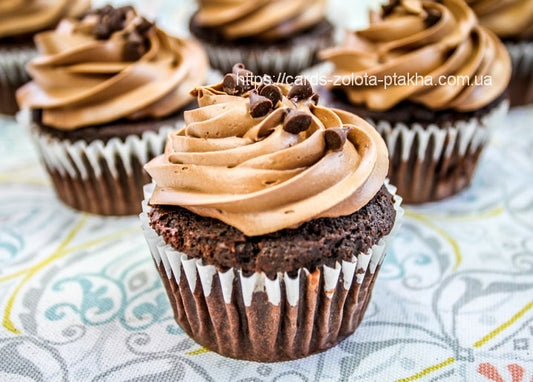 Nahaufnahme von Schokoladen-Cupcakes mit Sahnehaube und Schokostreuseln auf floraler Serviette