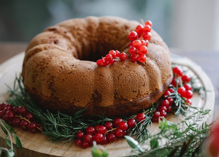 Spiced Christmas bundt cake on a wooden board with rosemary and viburnum berries