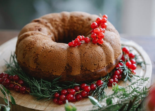 Spiced Christmas bundt cake on a wooden board with rosemary and viburnum berries
