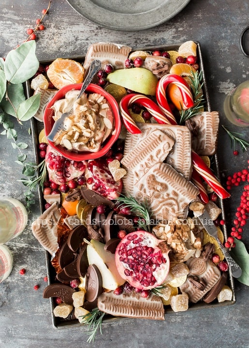 Weihnachtliches Dessertbrett mit geprägten Keksen, Zuckerstangen, Granatapfel und Birnen