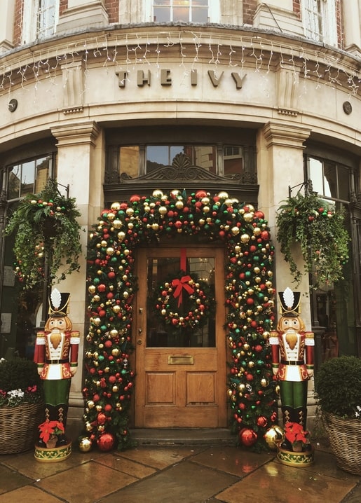 Doorway wrapped in Christmas garland with a red-bowed wreath and two nutcracker soldier statues