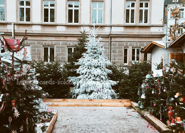 Schneebedeckte Tanne im europäischen Innenhof zwischen geschmückten Marktbäumen